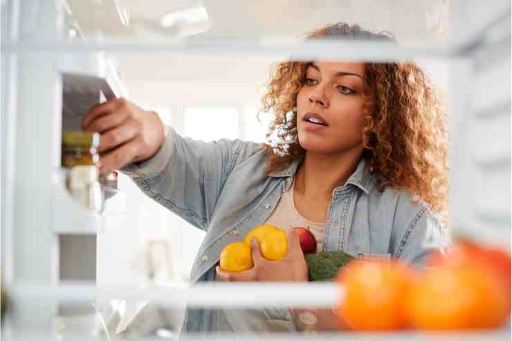 donna che sistema alimenti nel frigo