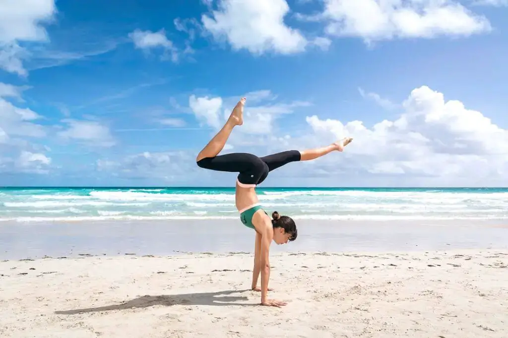 donna che fa yoga in spiaggia