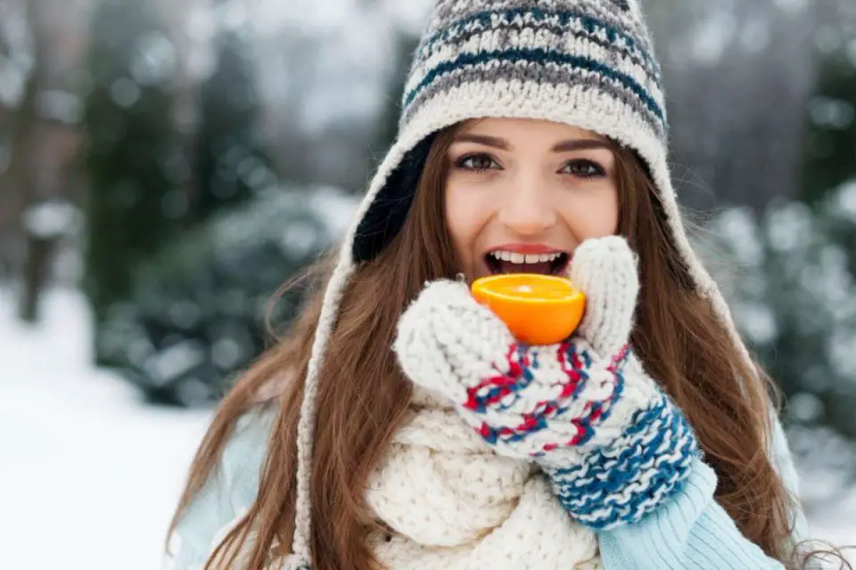 ragazza sulla neve che mangia arancia