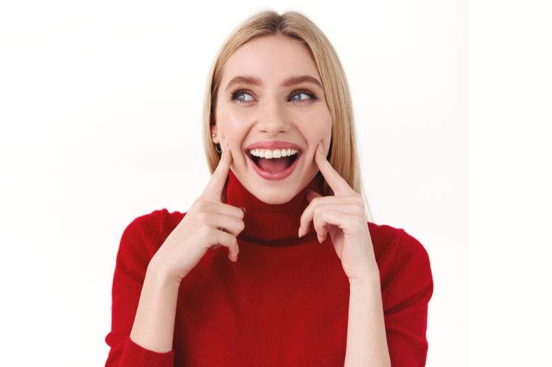 ragazza con denti bianchi perfetti e maglione rosso dolcevita